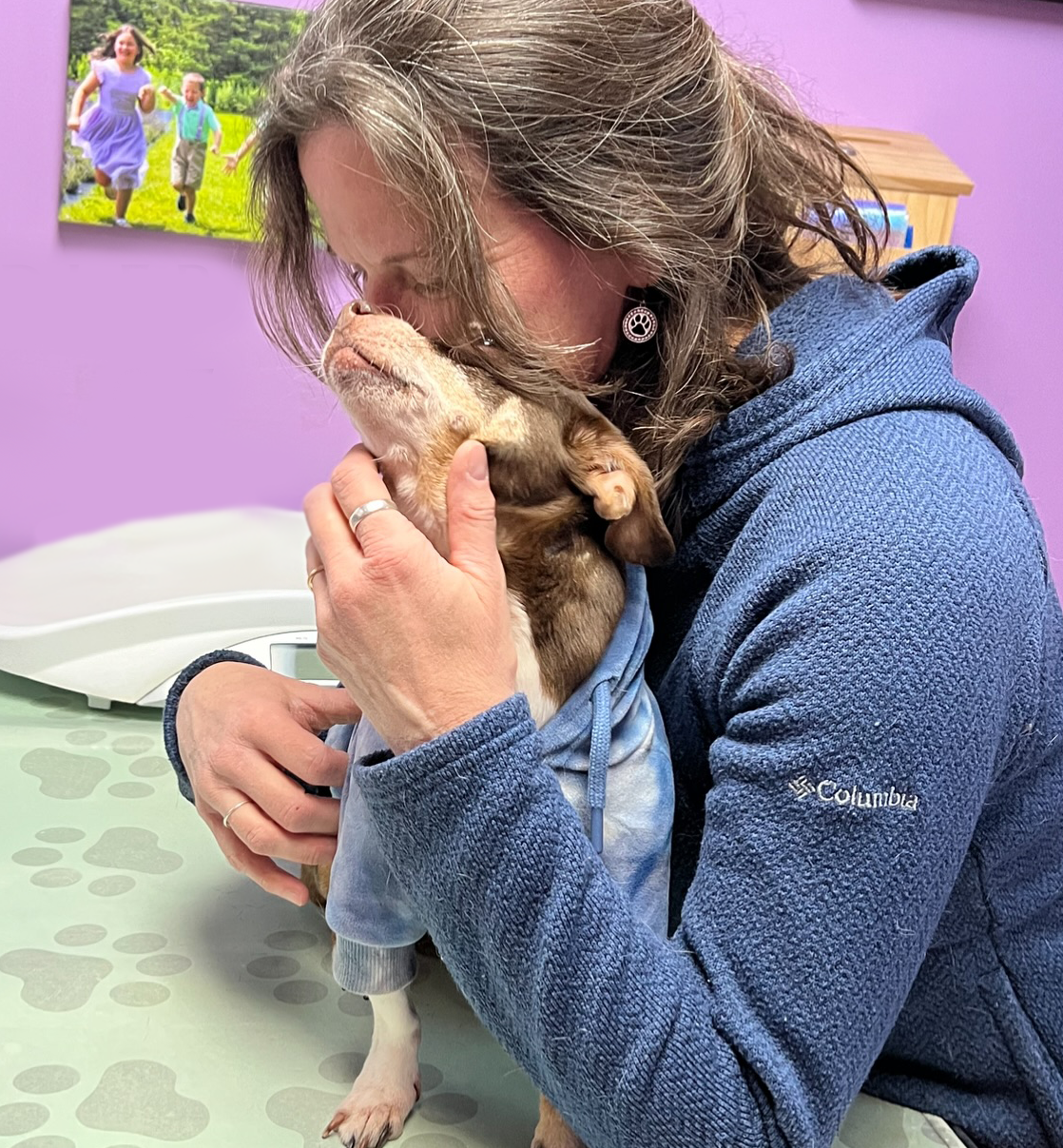 A person hugs a small dog